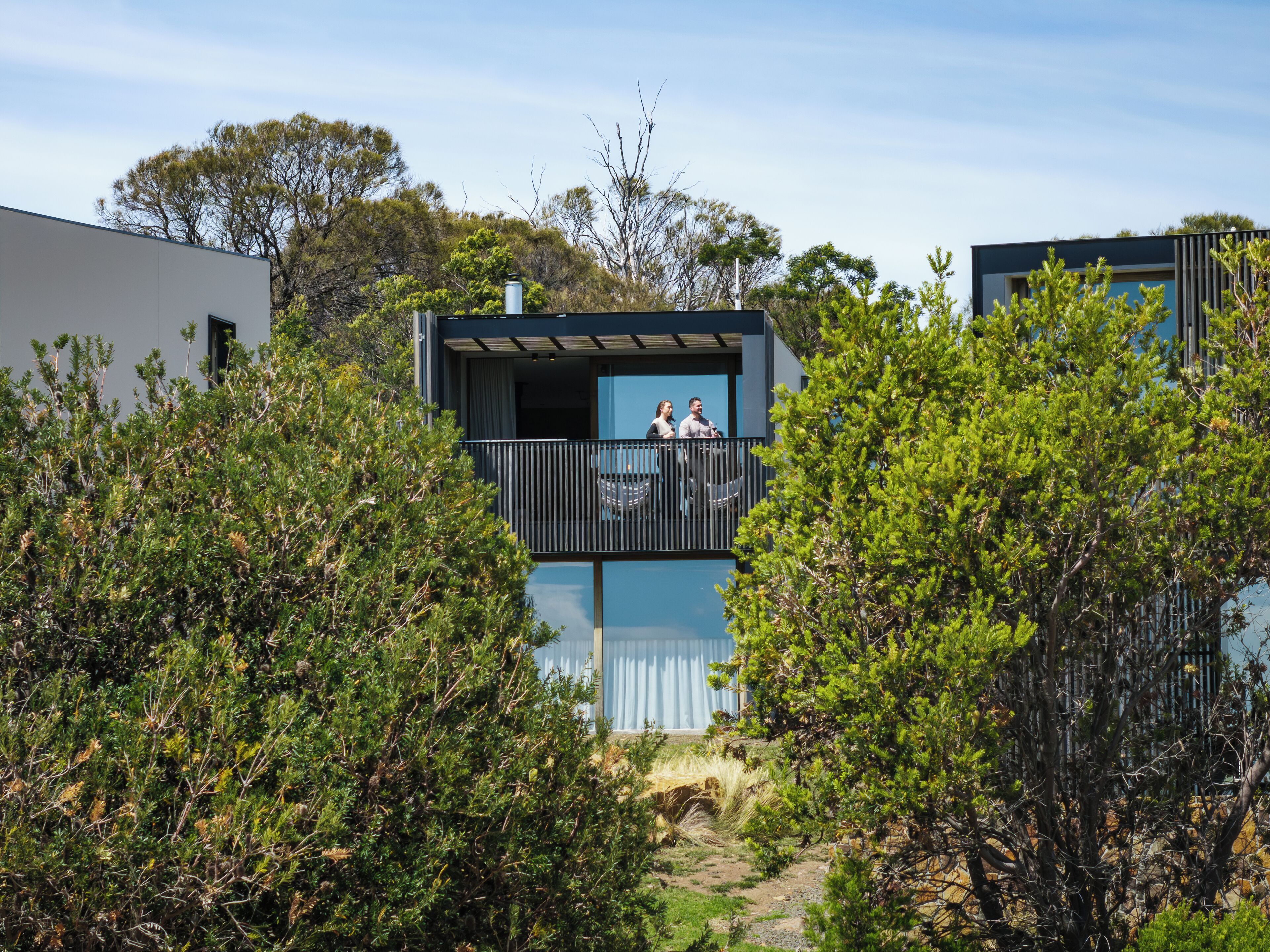 A modern building with a balcony overlooking a garden.