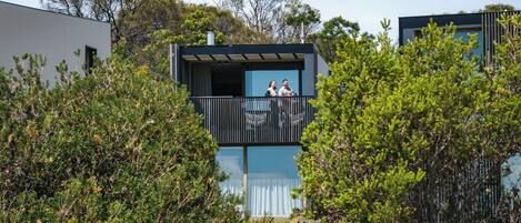 A modern building with a balcony overlooking a garden.