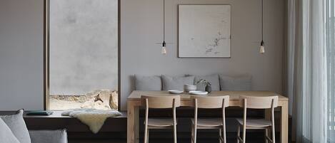 Un comedor moderno con una mesa de madera, cuatro sillas y un ventanal con cortinas.