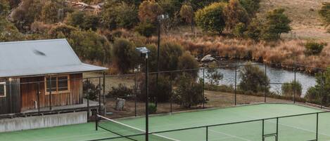 A tennis court with a pool in the foreground.