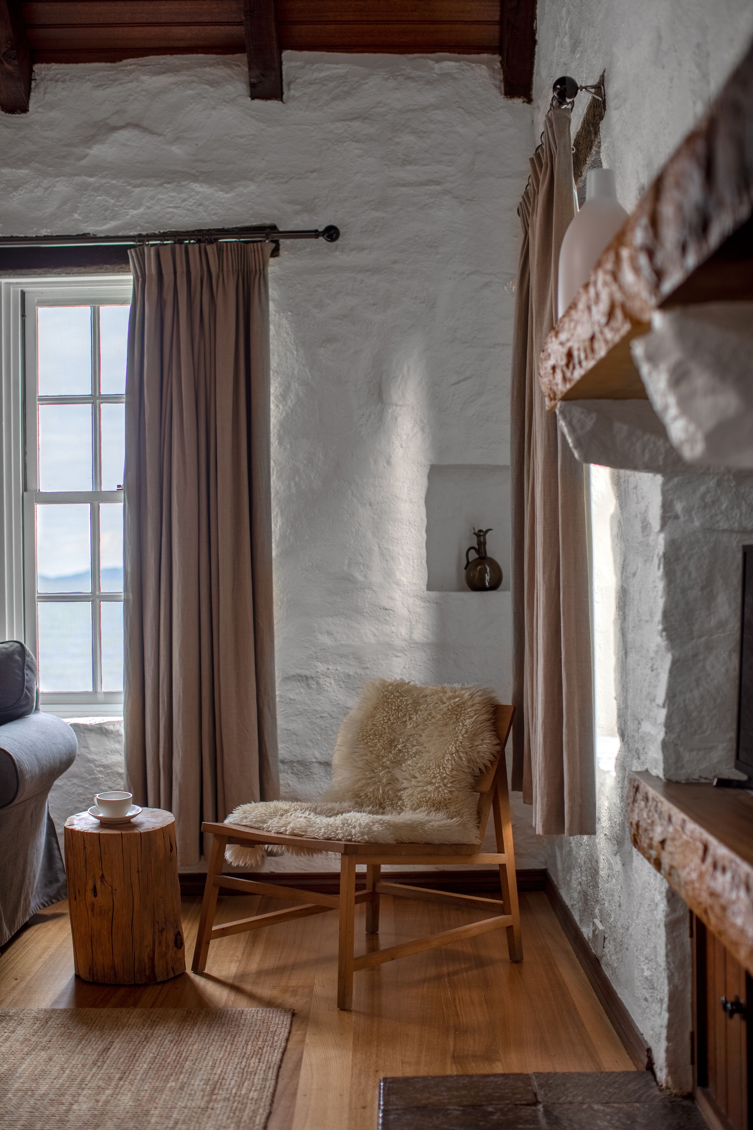 A cozy room with a wooden chair, a small round table, and a window with curtains.