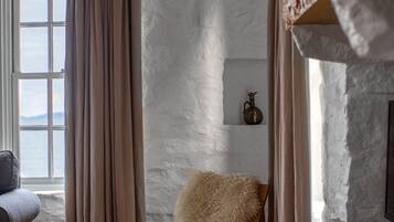 A cozy room with a wooden chair, a small round table, and a window with curtains.