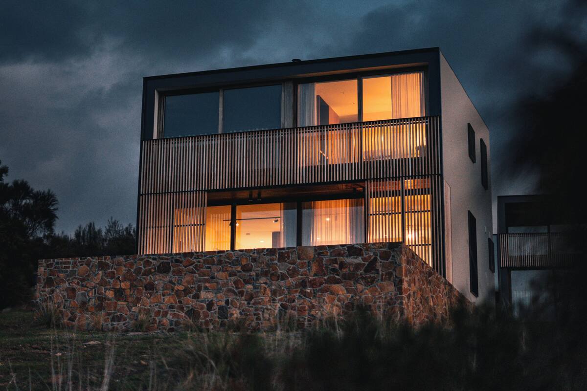 A modern two-story house with large windows and a stone foundation.