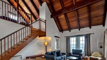 Amplia sala de estar con escalera de madera, un sofá, una silla y una mesa.