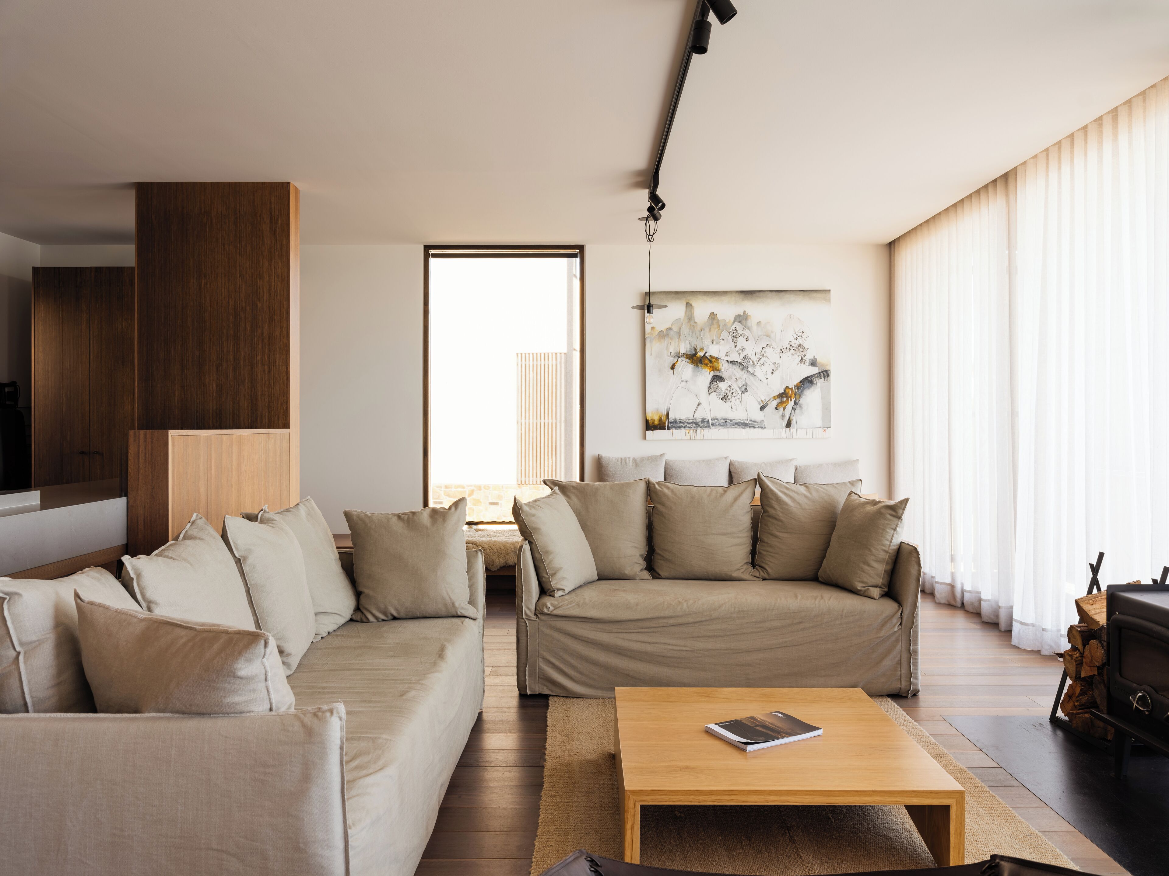 A modern living room with two sofas, a coffee table, and a painting on the wall.