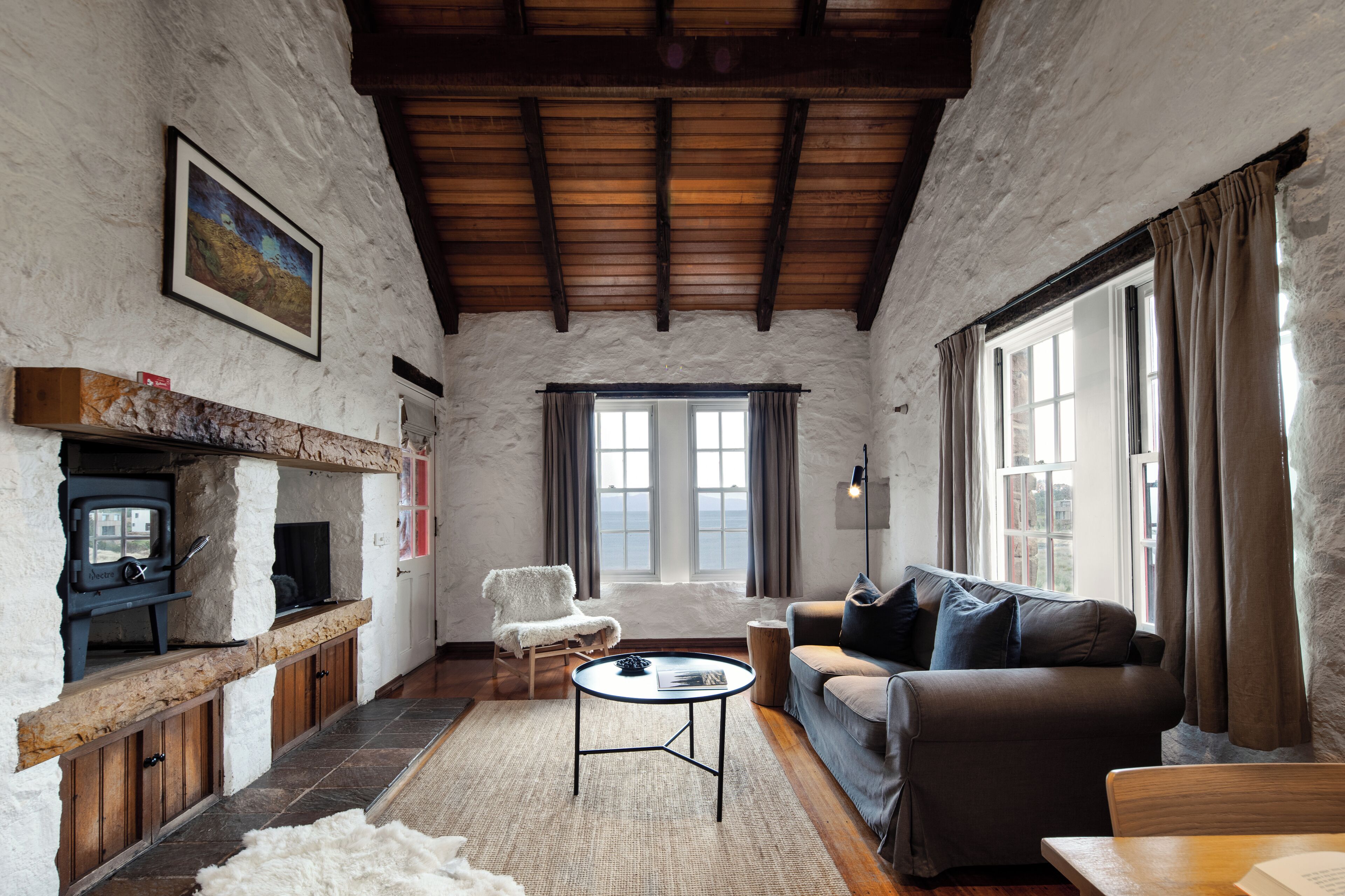 A cozy living room with a fireplace, a sofa, a coffee table, and a view of the outdoors.