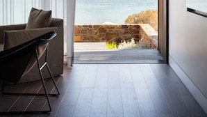 Et moderne værelse med stort vindue og havudsigt, en sofa samt minimalistisk indretning.