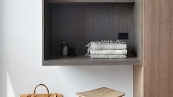Habitación minimalista con un armario de madera, una estantería con un jarrón, un cuadro enmarcado y una mesita con un bolso.