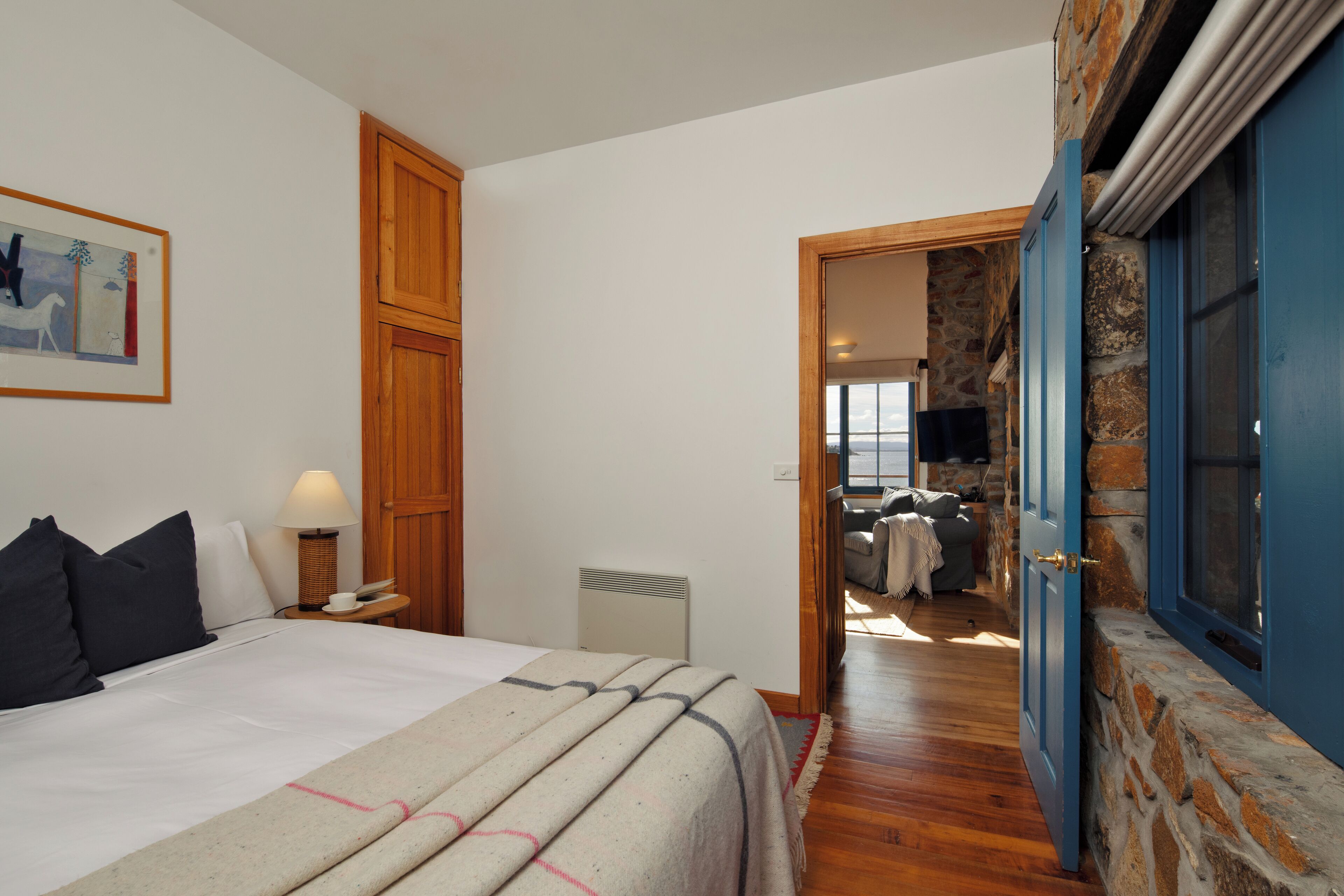 A bedroom with a bed, bedside lamp, and a painting on the wall.