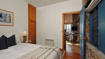 A bedroom with a bed, bedside lamp, and a painting on the wall.