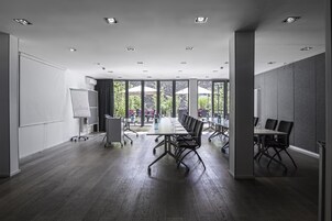 A modern conference room with a long table, black chairs, and a whiteboard.
