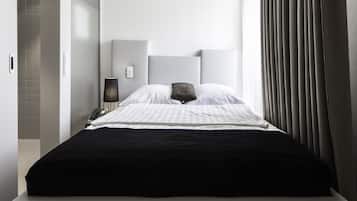 Ein modernes Hotelzimmer mit einem großen Bett, einem Nachttisch mit Lampe und Blick ins Freie.