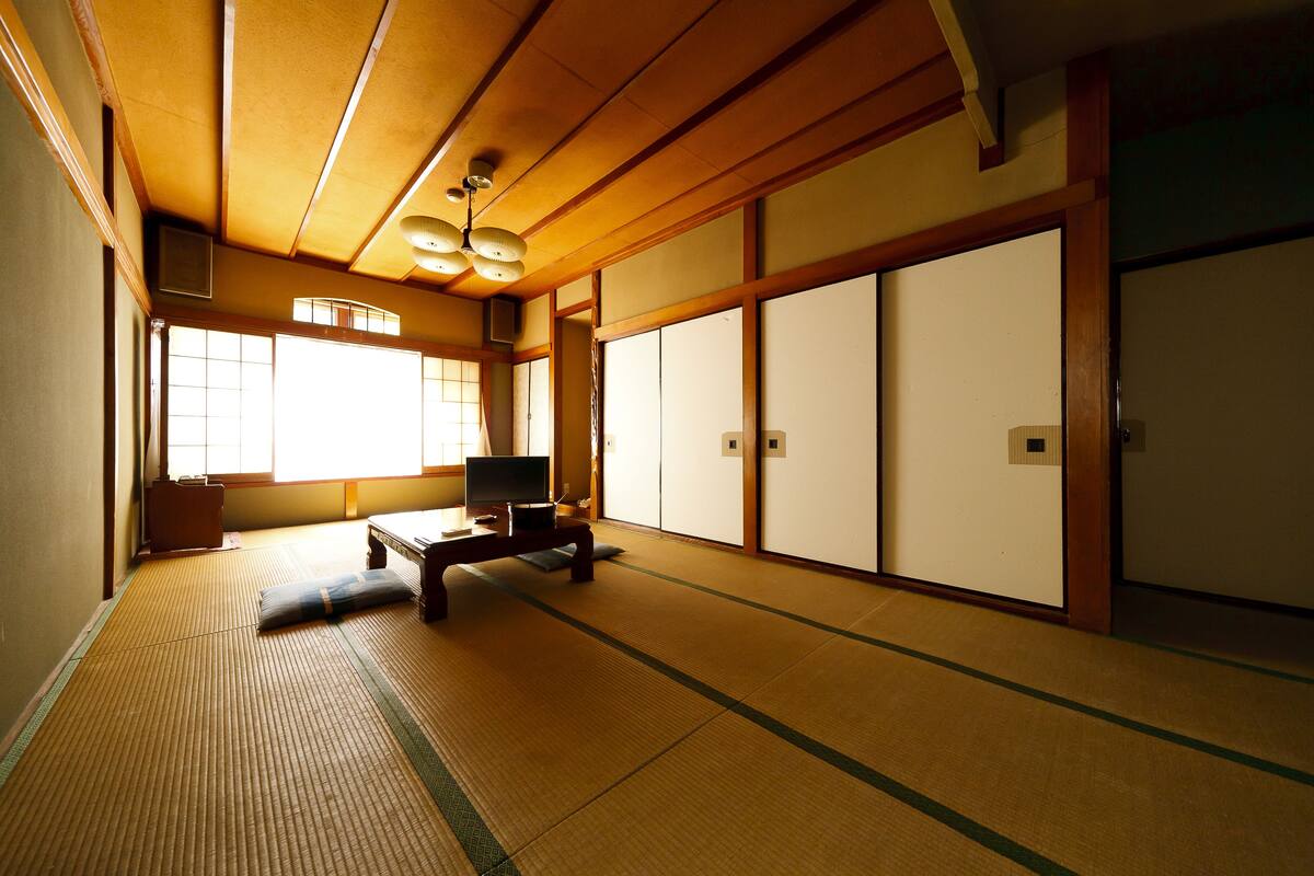 Una habitación japonesa tradicional con suelo de tatami, puertas correderas y un techo bajo de madera.
