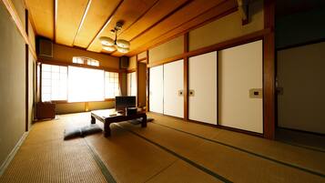 A traditional Japanese room with tatami flooring, sliding doors, and a low wooden ceiling.