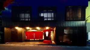 A modern building with a covered entrance, a red awning, and a small table with a chair. - Manten no Hoshi (Hakone)
