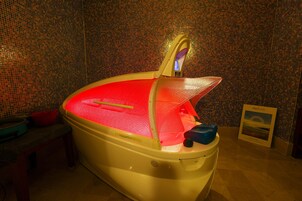 Una bañera con interior rojo, un grifo amarillo y una pared blanca con mosaicos.