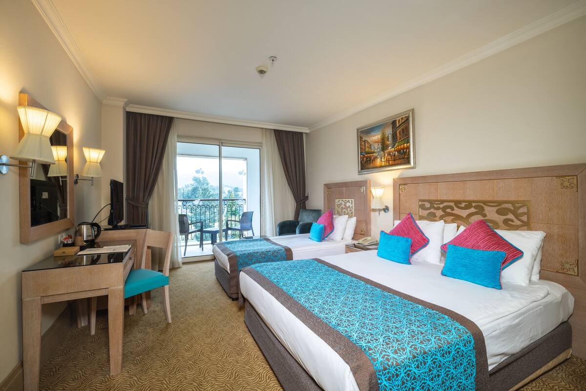 Une chambre d’hôtel avec deux lits, un bureau et un balcon.