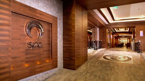 A modern hotel lobby with wooden paneling, a reception desk, and a patterned floor.