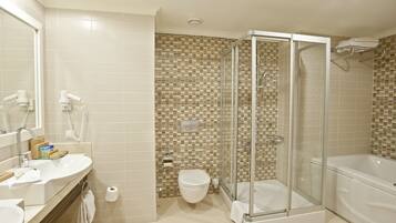A bathroom with a glass-enclosed shower, a bathtub, a toilet, and a sink with a mirror.
