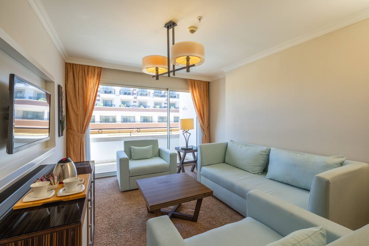 Une chambre d’hôtel moderne équipée d’un canapé, d’un fauteuil, d’une table basse et d’un téléviseur.