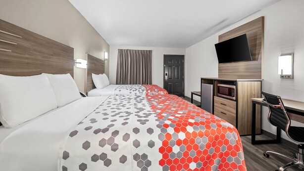 A hotel room with a bed, a desk, a chair, a TV, and a microwave. - Econo Lodge Biloxi Beach (Biloxi)