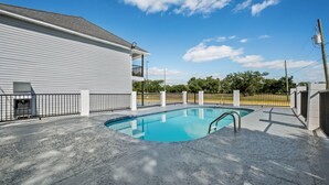 A swimming pool with a white building in the background. - Econo Lodge Biloxi Beach (Biloxi)
