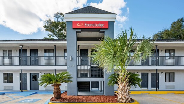 A two-story EconoLodge building with a central entrance, balconies, and a parking lot with palm trees. - Econo Lodge Biloxi Beach (Biloxi)