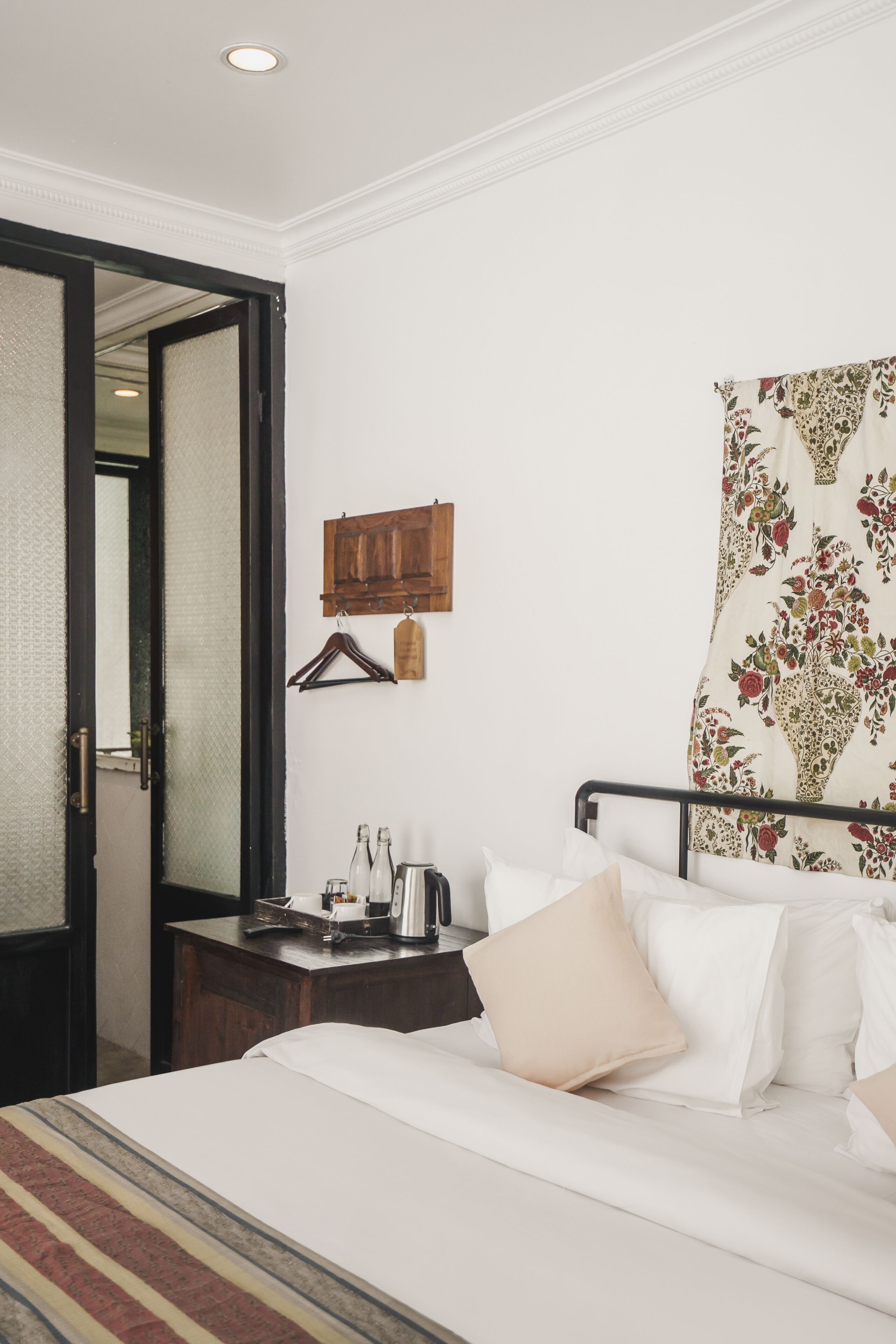 A hotel room with a bed, bedside table, and a mirror.