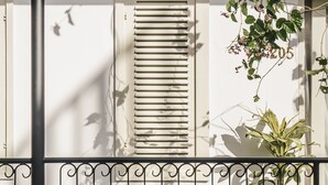 A balcony with a potted plant, a metal railing, and a window with shutters. - Brown Feather Batu Belig (Keroboken Kelod)