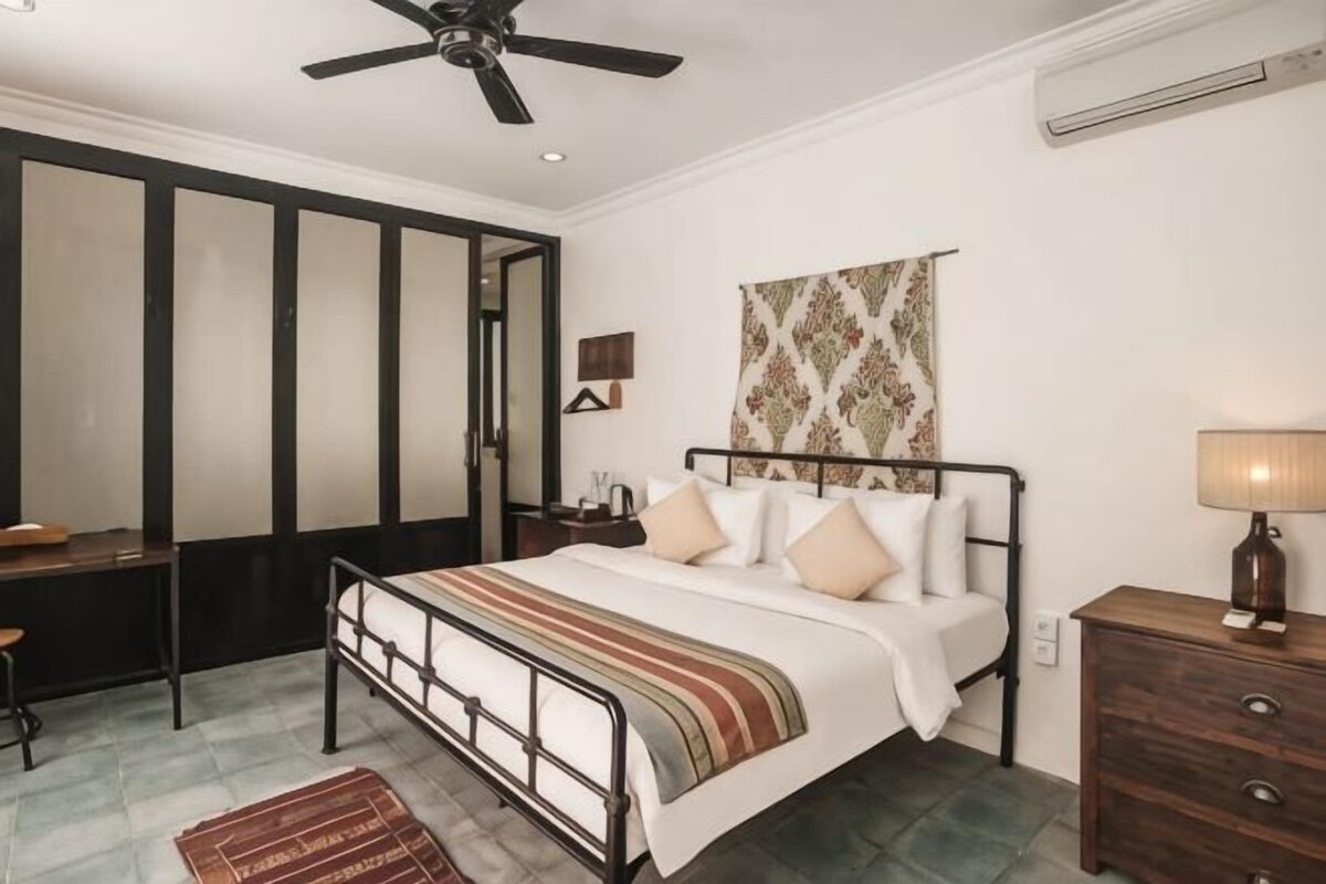 Un dormitorio con cama, mesita de noche, lámpara y ventilador de techo.