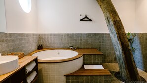 A modern bathroom with a freestanding bathtub, wooden shelves, and a hanging rack. - Brown Feather Batu Belig (Keroboken Kelod)
