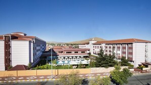 Un hotel con varias edificaciones, piscina y sombrillas exteriores.