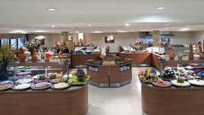Montaje de bufé con diversos alimentos y elementos decorativos en una sala amplia y bien iluminada.