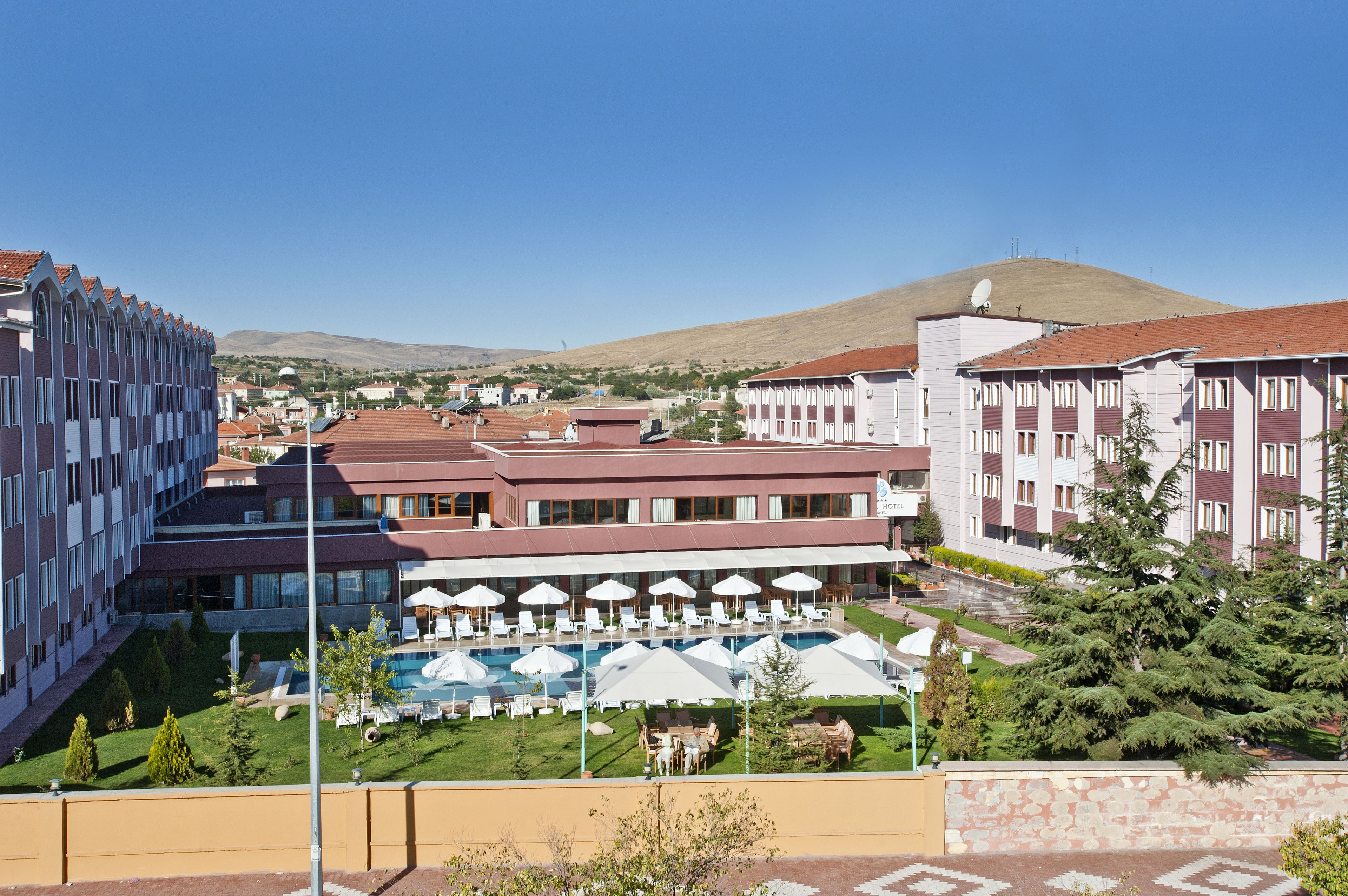 Un hotel con piscina, zona de estar al aire libre y vistas a una colina.