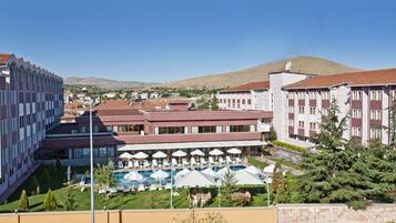 Un hotel con piscina, zona de estar al aire libre y vistas a una colina.