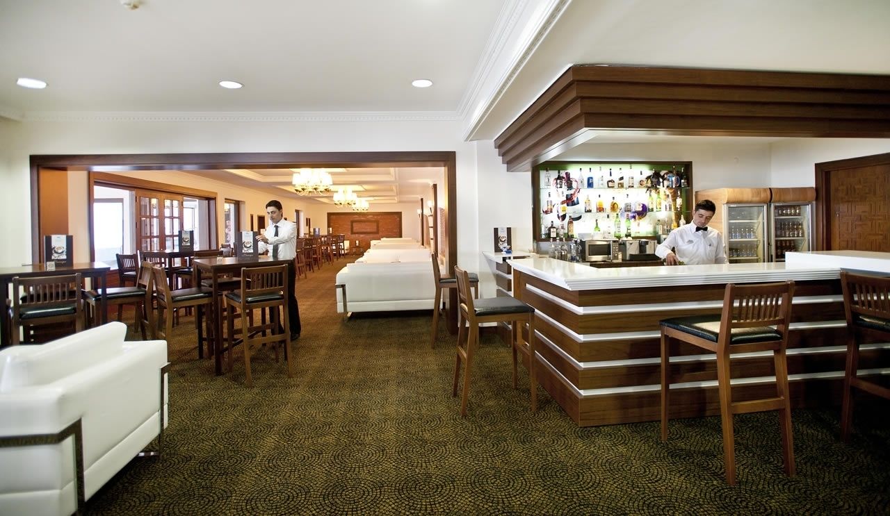 A hotel lobby with a bar area, multiple seating arrangements, and a reception desk.
