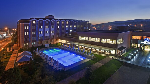 Un hotel con piscina, mobiliario exterior y una fachada bien iluminada.