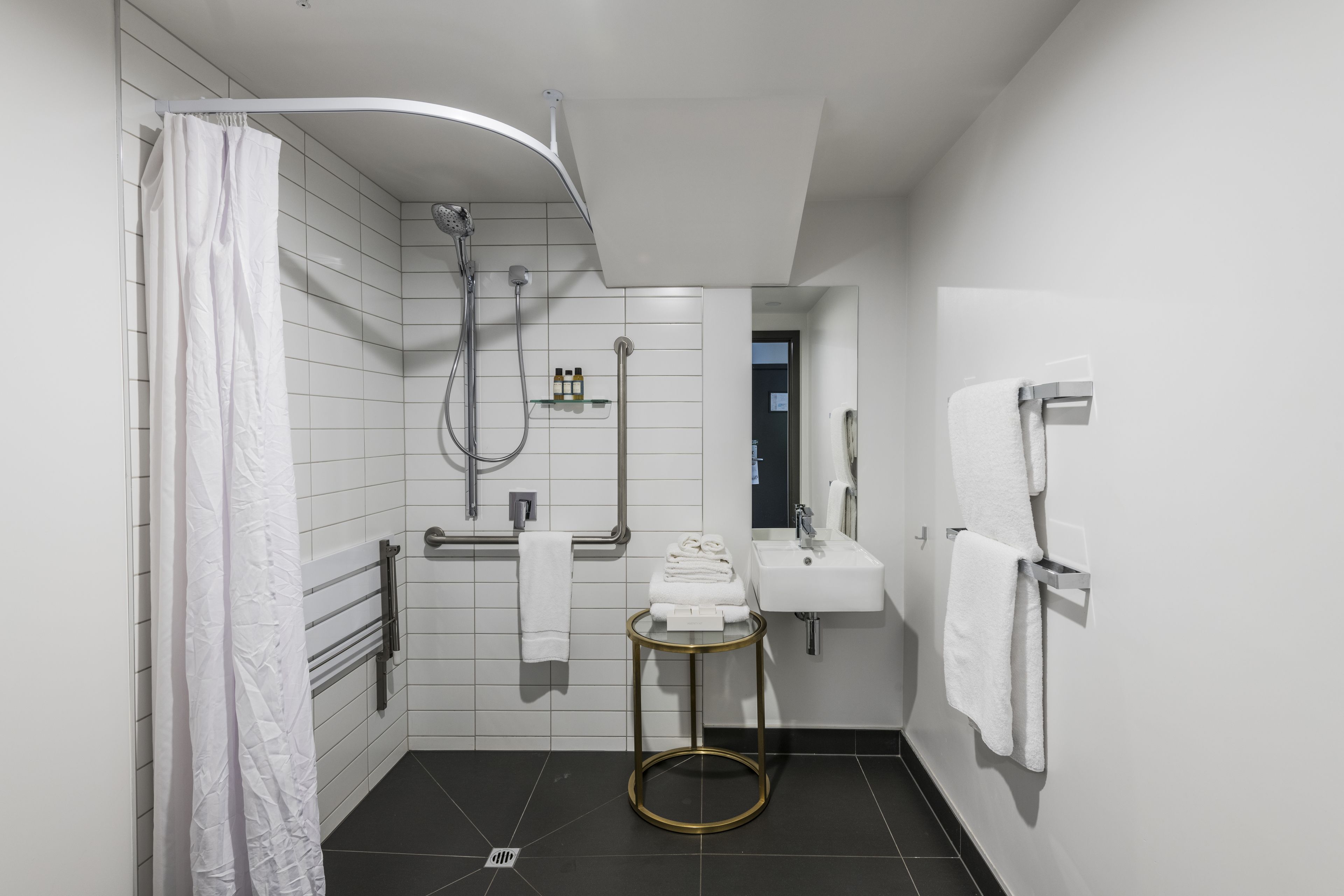 Un baño moderno con ducha, inodoro, lavabo y perchero para toallas.