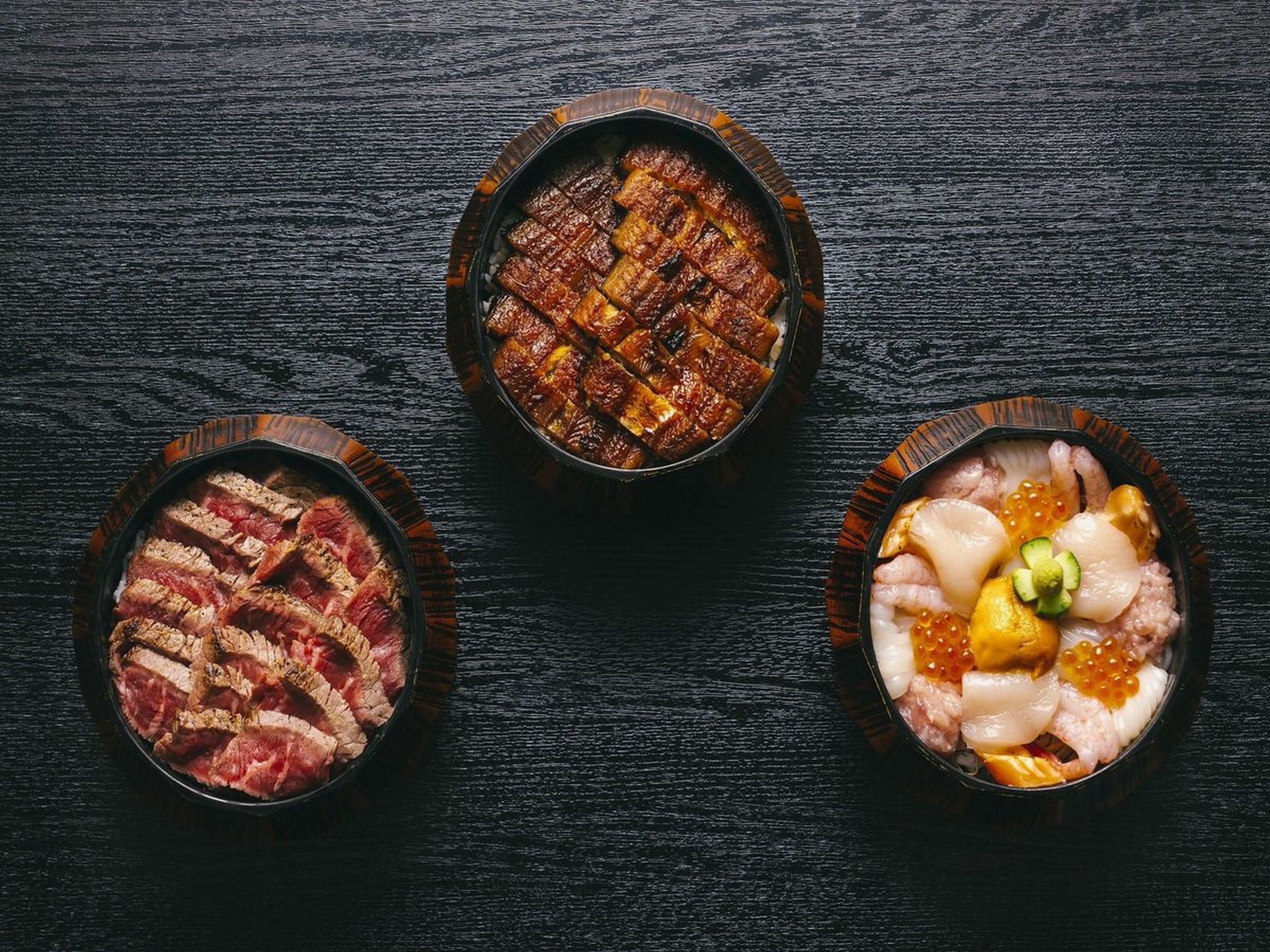 Three bowls of food on a dark wooden surface.