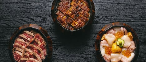 Three bowls of food on a dark wooden surface.
