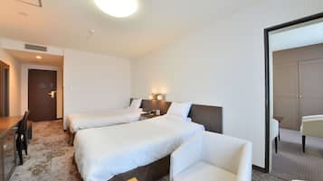 Une chambre d’hôtel avec deux lits, un bureau, une chaise et un miroir.