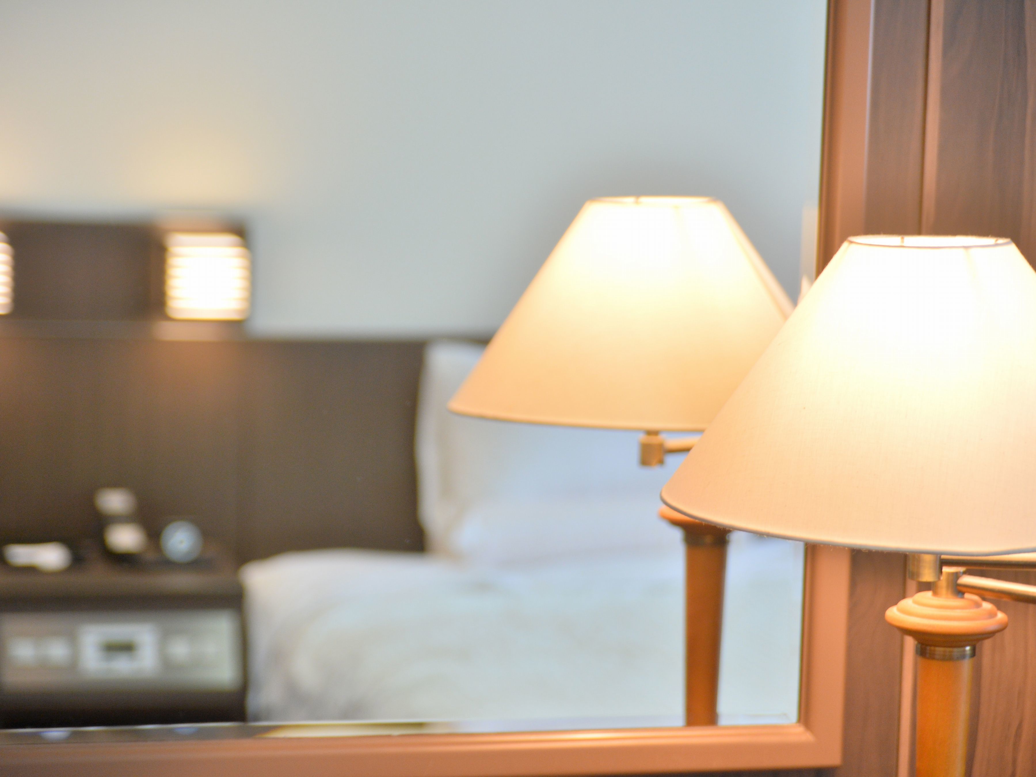 A hotel room with a bed, a nightstand, and two bedside lamps.