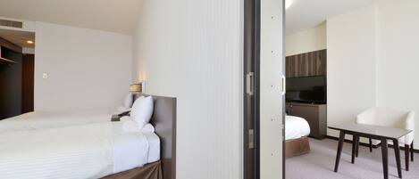 A hotel room with a bed, a desk, and a television.