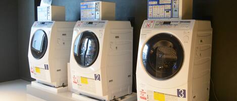 Three front-loading washing machines on display, each with a control panel and a label indicating their number.