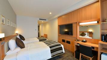 Habitación de hotel con dos camas, un escritorio, una silla, un televisor y una cafetera.