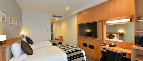 A hotel room with two beds, a desk, a chair, a television, and a coffee machine.