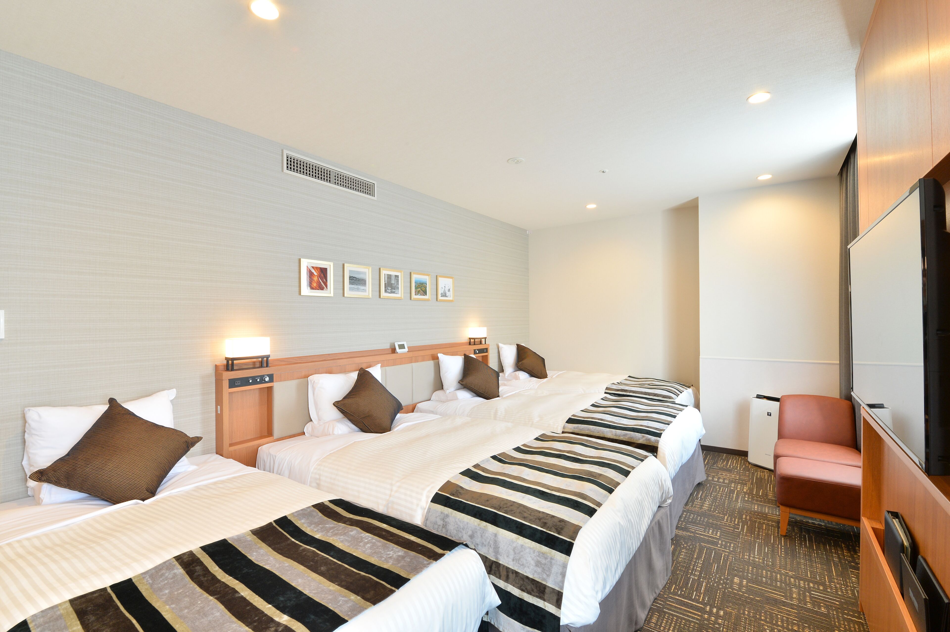 Ein Hotelzimmer mit zwei Betten, einem kleinen Schreibtisch, einem Stuhl und einem Fernseher.