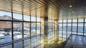 A spacious indoor area with large windows offering views of a cityscape and a body of water. - Hakodate Kokusai Hotel (Hakodate)