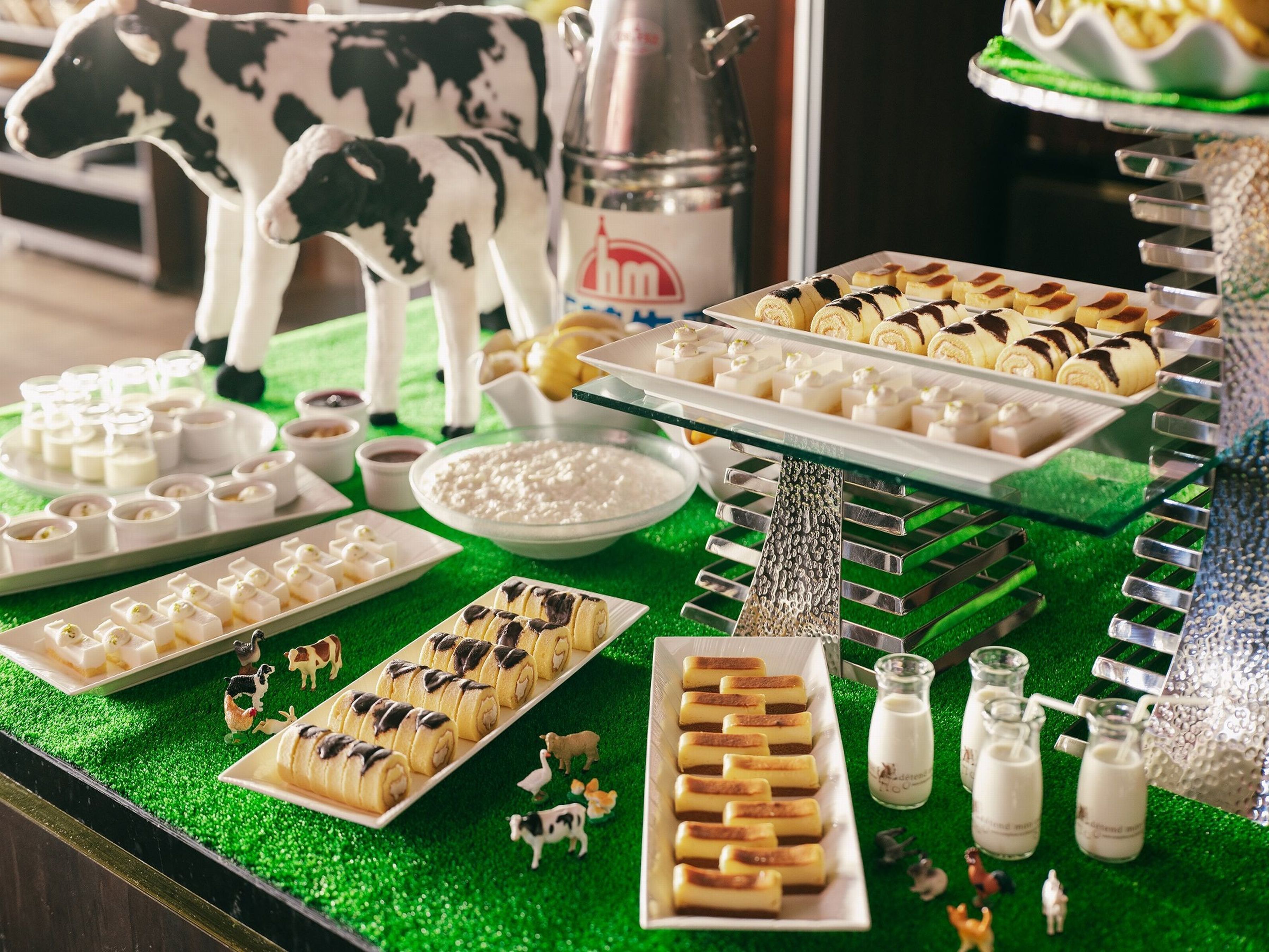 A buffet table with various food items, including pastries and desserts, arranged on a green surface.