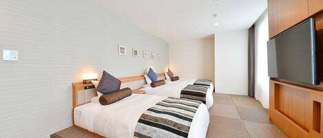 A hotel room with two beds, a flat-screen TV, and a large window.